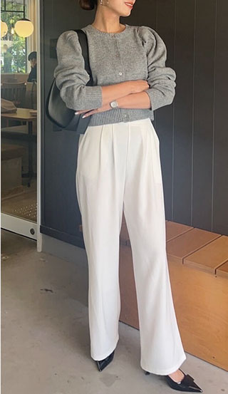 グレーのショート丈カーデにオフホワイトのハイウエストワイドパンツを着た女性の画像