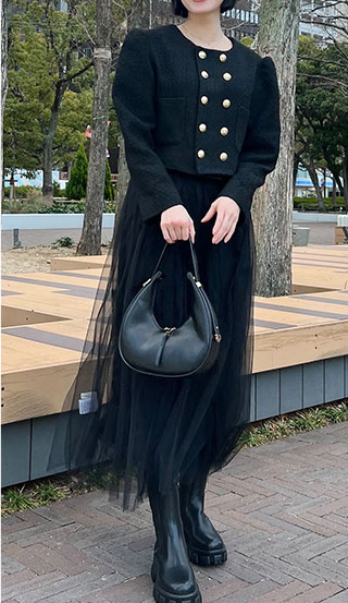 ツイードのショート丈ジャケットに黒のチュールフレアスカートを着た女性の画像