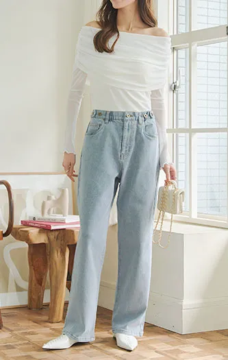 ピュアホワイトのオフショルトップスにデニムパンツをコーディネートした女性の画像